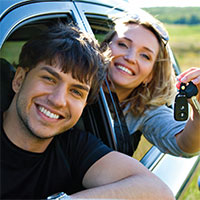 Couple leaning out of car window holding keys.